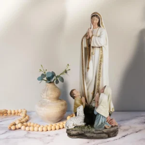 Lifestyle tabletop display of the 12-Inch Our Lady of Fatima Statue with a vase and wooden rosary beads Wholesale 12-Inch Hand-Painted Resin Our Lady of Fatima Statue with Children Figurine